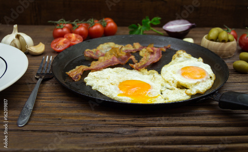 Fried eggs and bacon in the frying pan. Gourmet breakfast