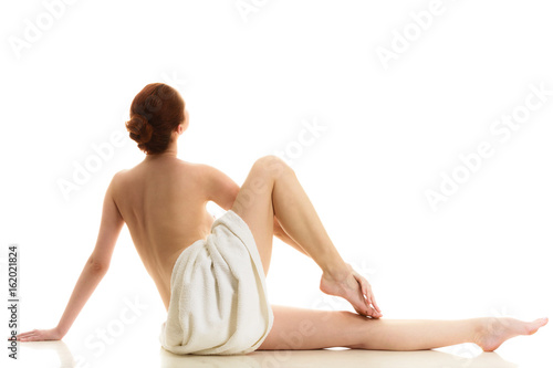 Sitting naked woman in towel showing feet
