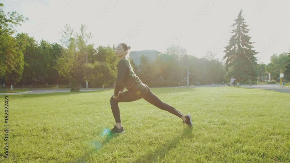 Young girl training yoga in the park among the sun glare 4K Young girl training yoga in the park among the sun glare 4K