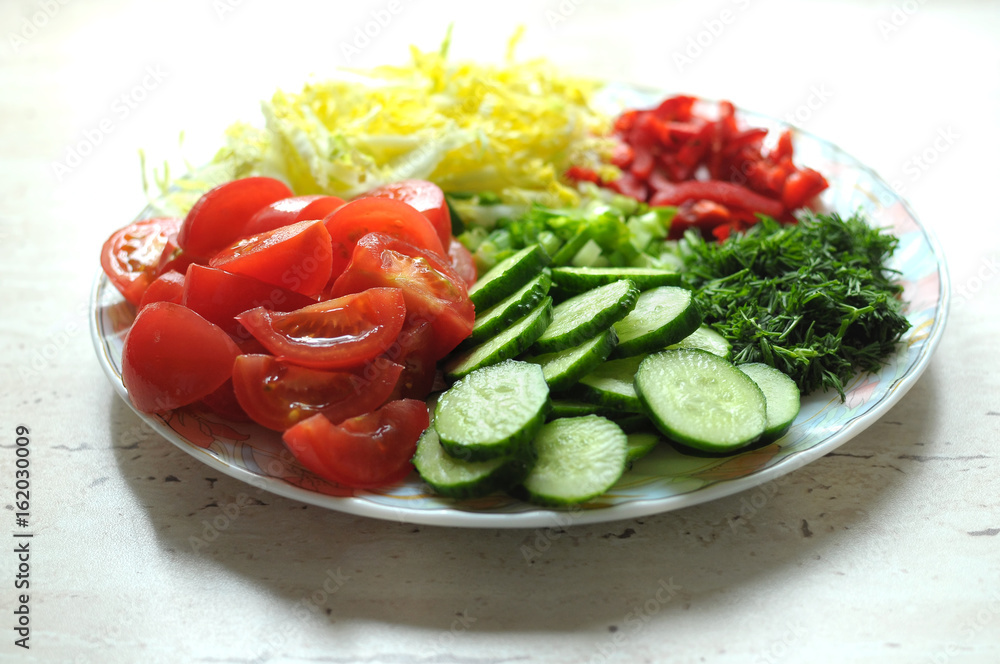 Fresh organic sliced vegetables on the white plate on the wooden table. Close up, selective focus. Fresh organic sliced vegetables on the white plate on the wooden table. Close up, selective focus.