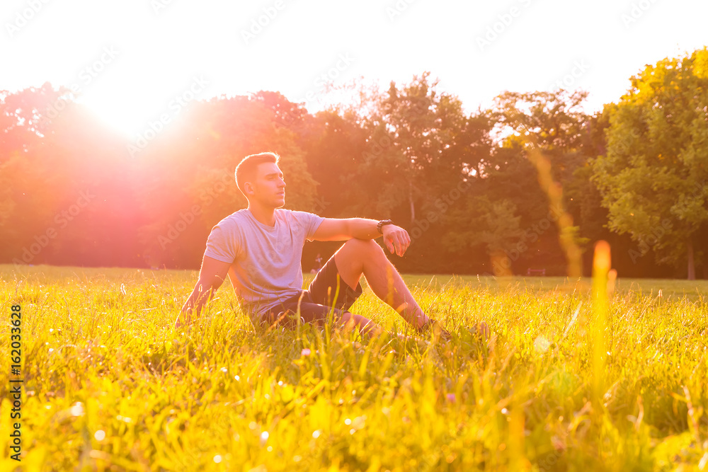 Fototapeta premium A young man sitting in the Grass
