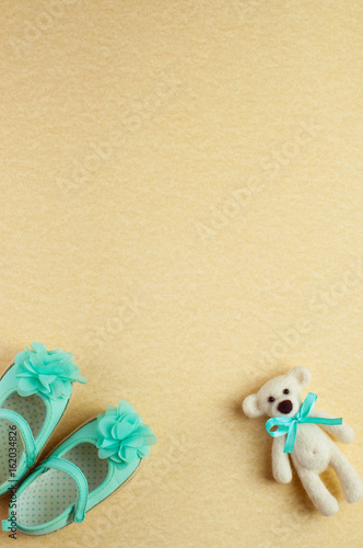 Baby background with bear toy and turquoise shoes for baby girl