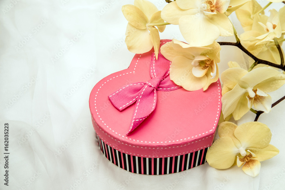 gift box in form of heart on the background of the yellow orchid gift box in form of heart on the background of the yellow orchid