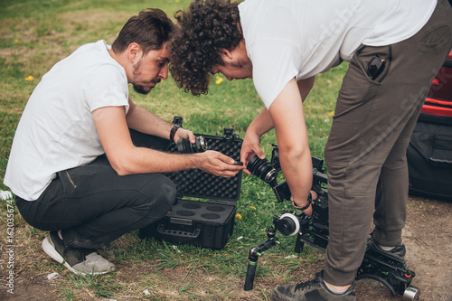 Behind the scene. Cameraman and assistant changes lens on camera photo