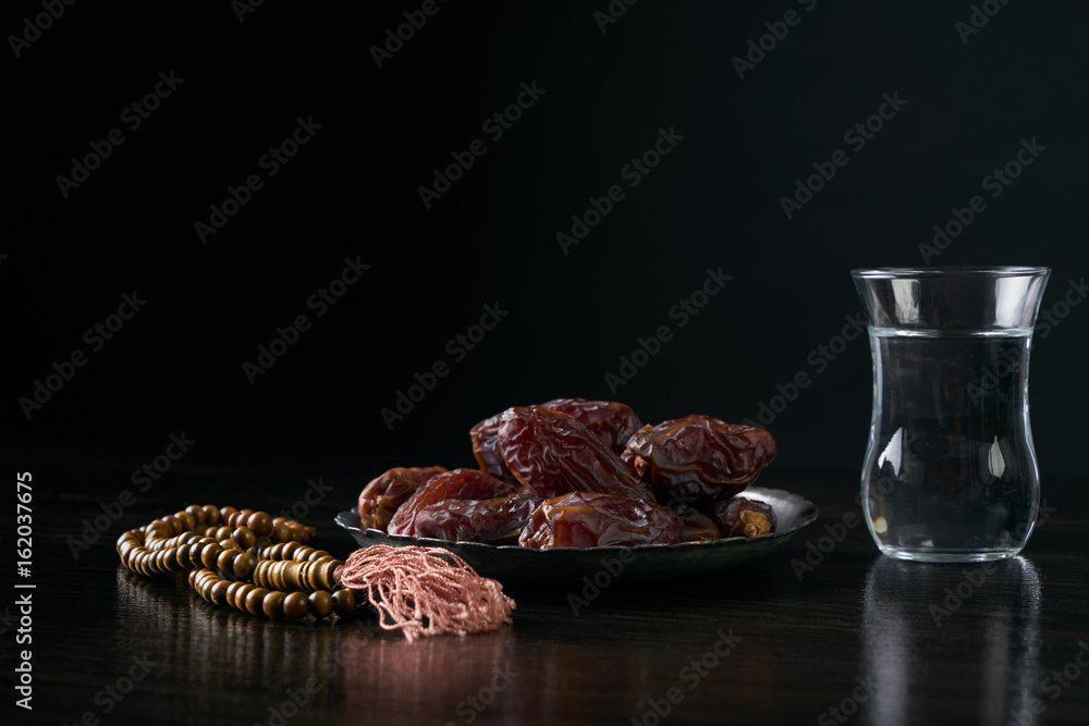 Ramadan ramazan kareem. Glass of water and dry dates for iftar party  holidays on black wooden table isolated on black background with copy  space. Stock Photo | Adobe Stock
