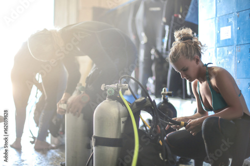 Three scuba divers dressing up for a dive session