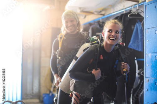 Guy helping a girl dressing up with scuba diver's equipment
