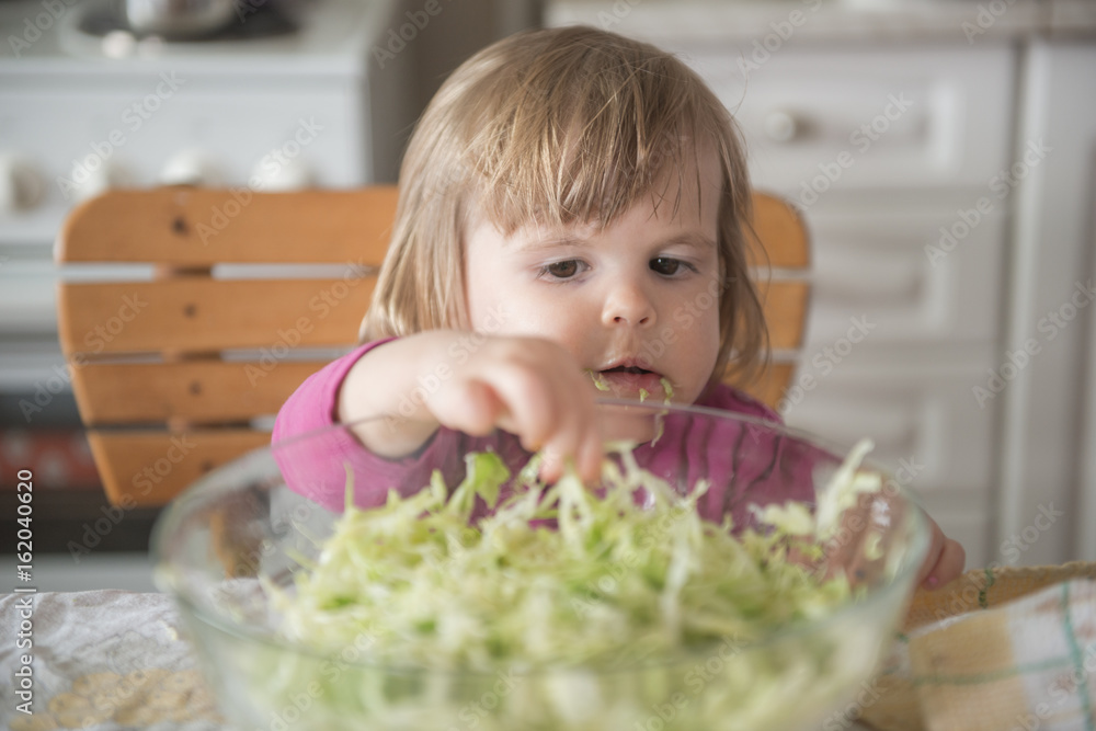 Little girl picking at cabbage from salad bowl Little girl picking at cabbage from salad bowl