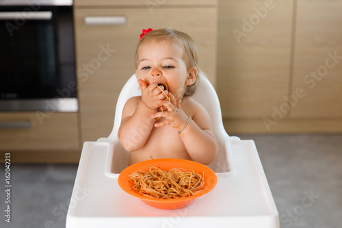 Toddler eating handful of pasta photo