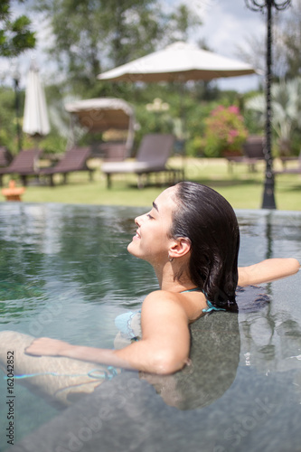 Happy young woman relaxing in hotel swimming pool