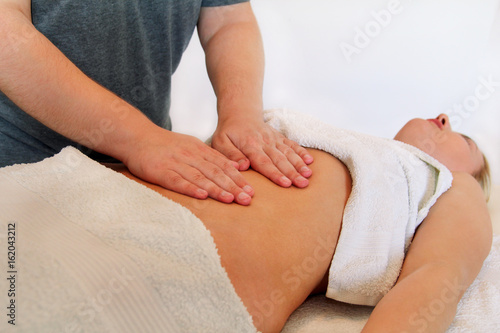 Belly massage in massage studio. In spa professional wellness center. Masseur massaging girls belly. Body and health care, medicine concept. Pretty women having massage in the spa body massage salon.