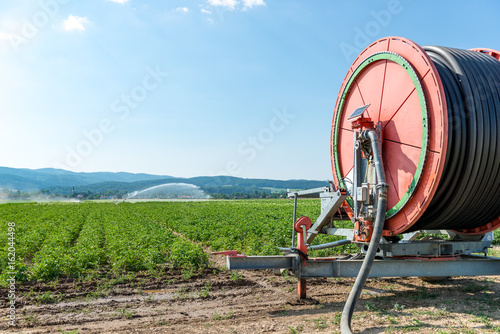 agricultural hose reel of a irrigation system with sprinkler in the background