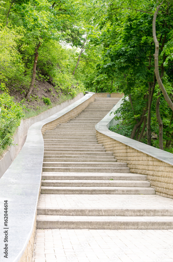 Stone steps are Stairs rung leading upwards against the background of green trees Stone steps are Stairs rung leading upwards against the background of green trees