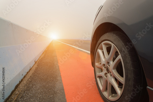 Close up of wheel car parking on the asphalt road with sunlight.
