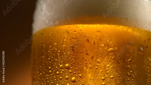 Cold beer in a glass with water drops. Craft beer close up. Rotation 360 degrees. 4K UHD video 3840x2160