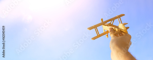 Billede på lærred close up of man's hand holding toy airplane against sunset sky