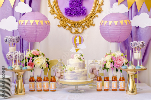 Interior decoration for a child's birthday is one year in purple colors. Candy, macaroon, tiered cake, and juices.