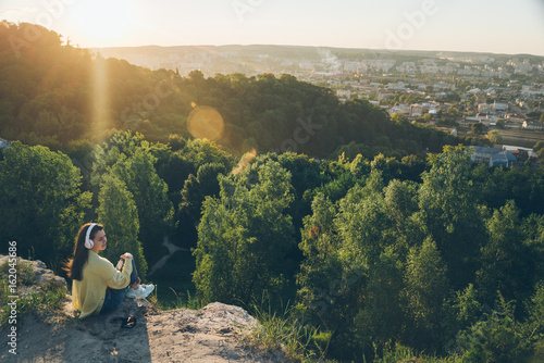 young pretty woman listing music on the top of the hill photo