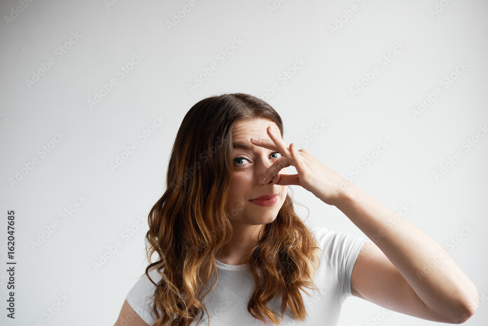 Bad smelling concept. Studio shot of disgusted young European woman pinching her nose because of awful stink coming out from garbage or spoiled food. Negative human emotions and nasty feelings Bad smelling concept. Studio shot of disgusted young European woman pinching her nose because of awful stink coming out from garbage or spoiled food. Negative human emotions and nasty feelings