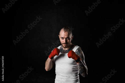 Martial arts, sports, kickboxing, fitness and bodybuilding. Waist up portrait of handsome athletic muscular kickboxer dressed in white t-shirt, holding fists in front of him, showing his readiness © Anatoliy Karlyuk