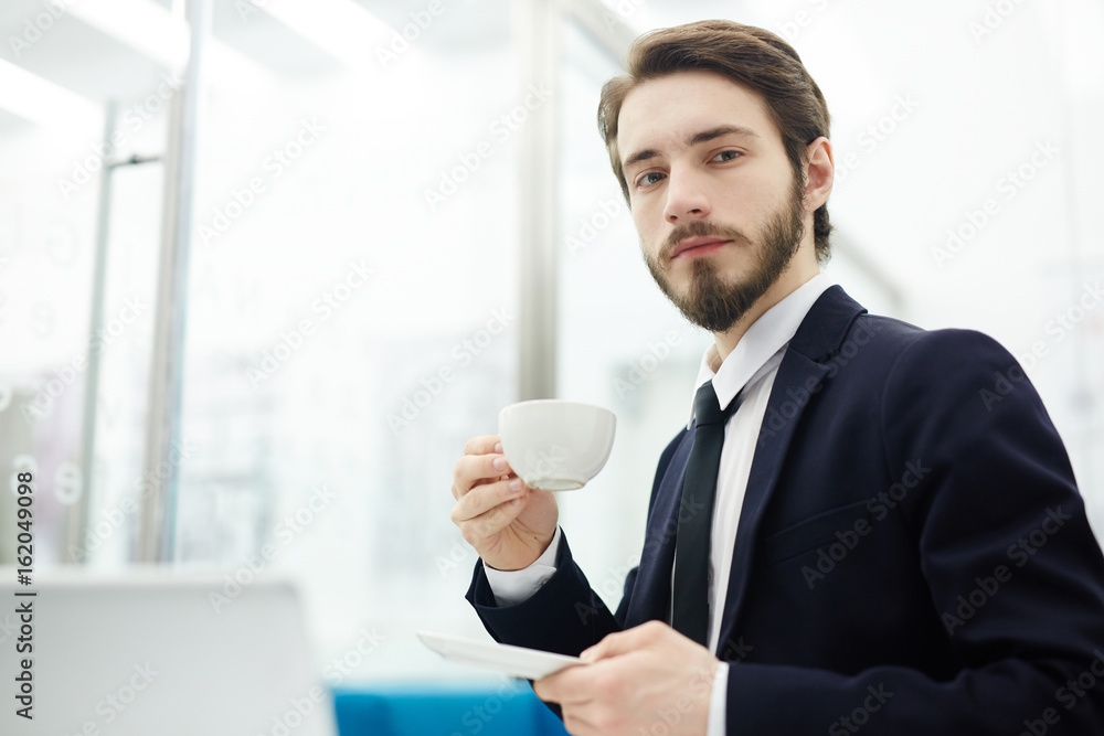 Young entrepreneur with cup of tea looking at camera at break Young entrepreneur with cup of tea looking at camera at break