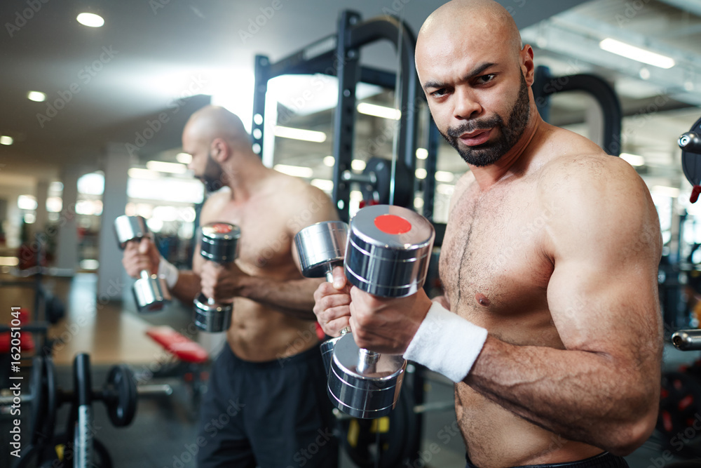Young man looking at camera while exercising in gym Young man looking at camera while exercising in gym
