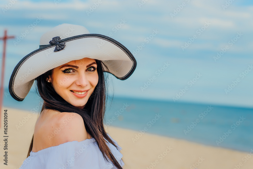 Woman in hat and white dress on the background of the sea