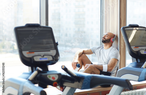 Restful sportsman enjoying music in headphones