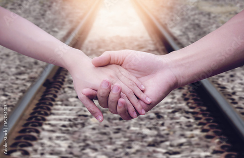 Close up woman holding man hand at the railway. photo