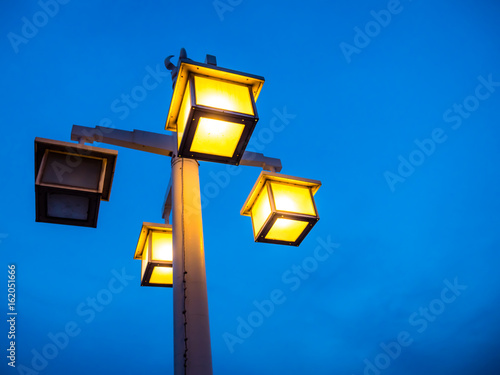 Vintage electric light pole on walkway in park. Beautiful light in low light time.