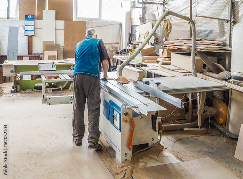 Worker sawing wood panel saw machine for furniture factory. Circular saw. © sablinstanislav