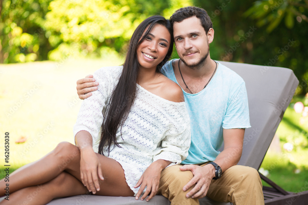 Man Embracing Asian Girlfriend on Chaise Longue Man Embracing Asian Girlfriend on Chaise Longue