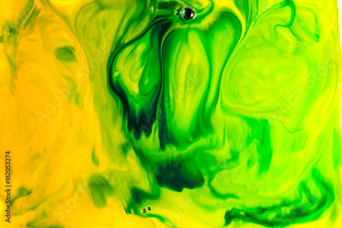Yellow and green oil paint on water abstract background.