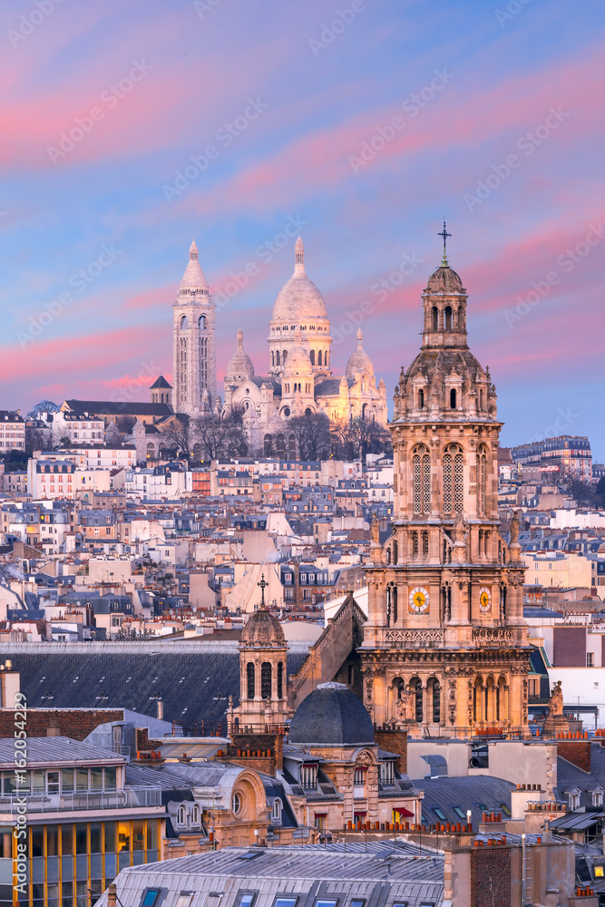 Aerial view of Sacre-Coeur Basilica or Basilica of the Sacred Heart of Jesus at the butte Montmartre and Saint Trinity church at nice sunset, Paris, France