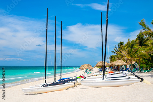 Photography Varadero beach in Cuba with sailboats and thatched umbrellas