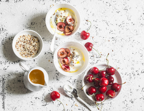 Greek yogurt with cherries and honey on white table, top view. Flat lay. Summer breakfast or snack