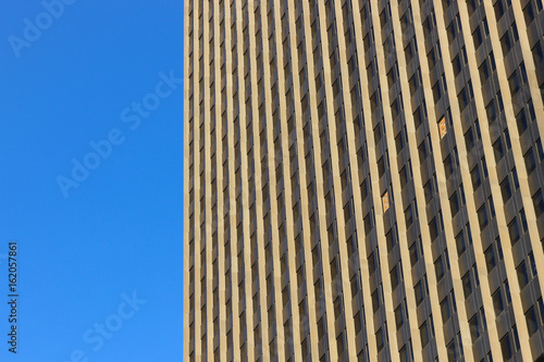 Skyscraper against clear blue sky. Geometric pattern of windows with two imperfections