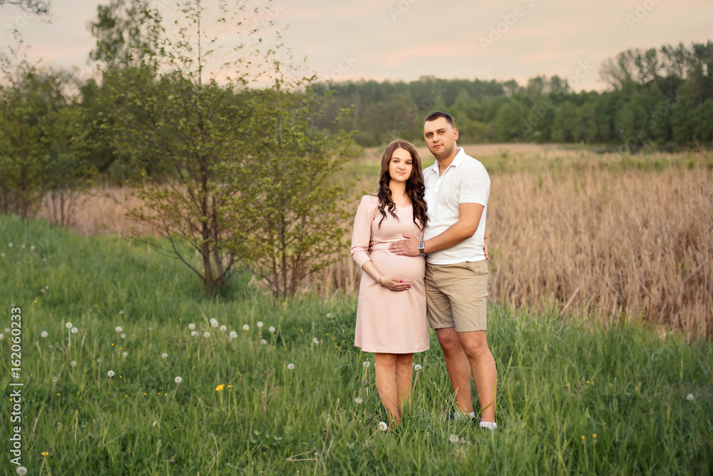 Family love couple in the forest park Woman pregnant Future parents in anticipation of the baby Family love couple in the forest park Woman pregnant Future parents in anticipation of the baby