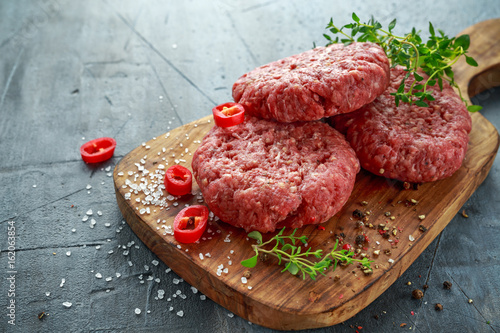 Home HandMade Raw Minced Beef steak burgers on wooden board. photo