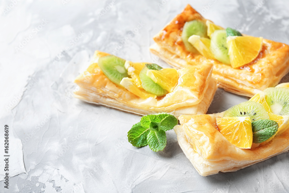 Delicious puff pastries with fruits and honey on grey background Delicious puff pastries with fruits and honey on grey background