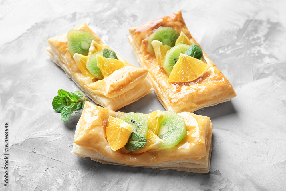 Delicious puff pastries with fruits and honey on grey background Delicious puff pastries with fruits and honey on grey background