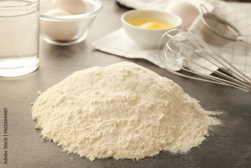 Heap of flour and ingredients for dough on grey table Heap of flour and ingredients for dough on grey table