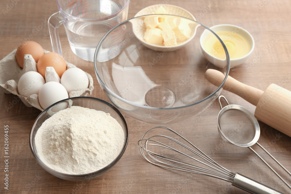 Bowl with flour and ingredients for dough on table Bowl with flour and ingredients for dough on table