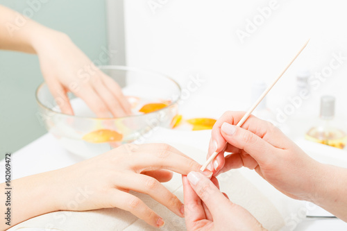 Preparing nails before manicure, pushing back cuticles