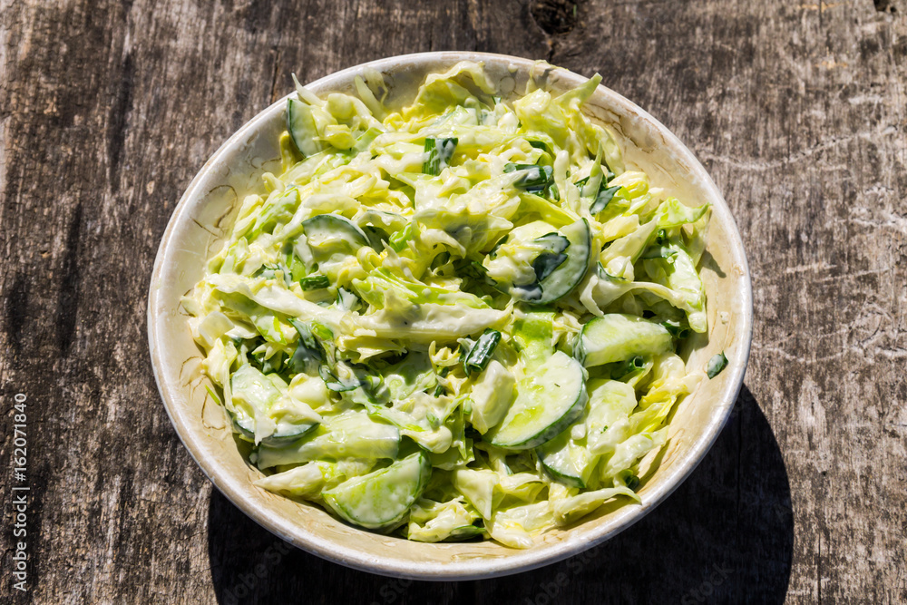 Spring salad with cabbage, cucumber, green onion, parsley and mayonnaise on wooden table Spring salad with cabbage, cucumber, green onion, parsley and mayonnaise on wooden table