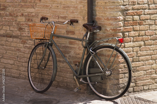 Vintage bike for picnic stands near the brick wall of Italian city.