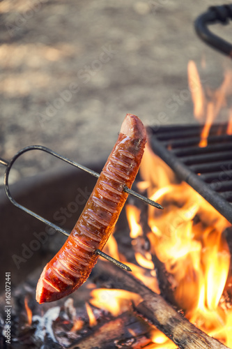 Preparing sausage on camp fire, camping food