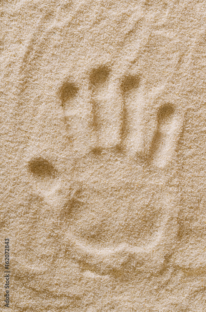 Handprint in the sand. Handmark and imprint of the left hand of an adult in dry ocherous sand. Macro photo close up from above. Handprint in the sand. Handmark and imprint of the left hand of an adult in dry ocherous sand. Macro photo close up from above.