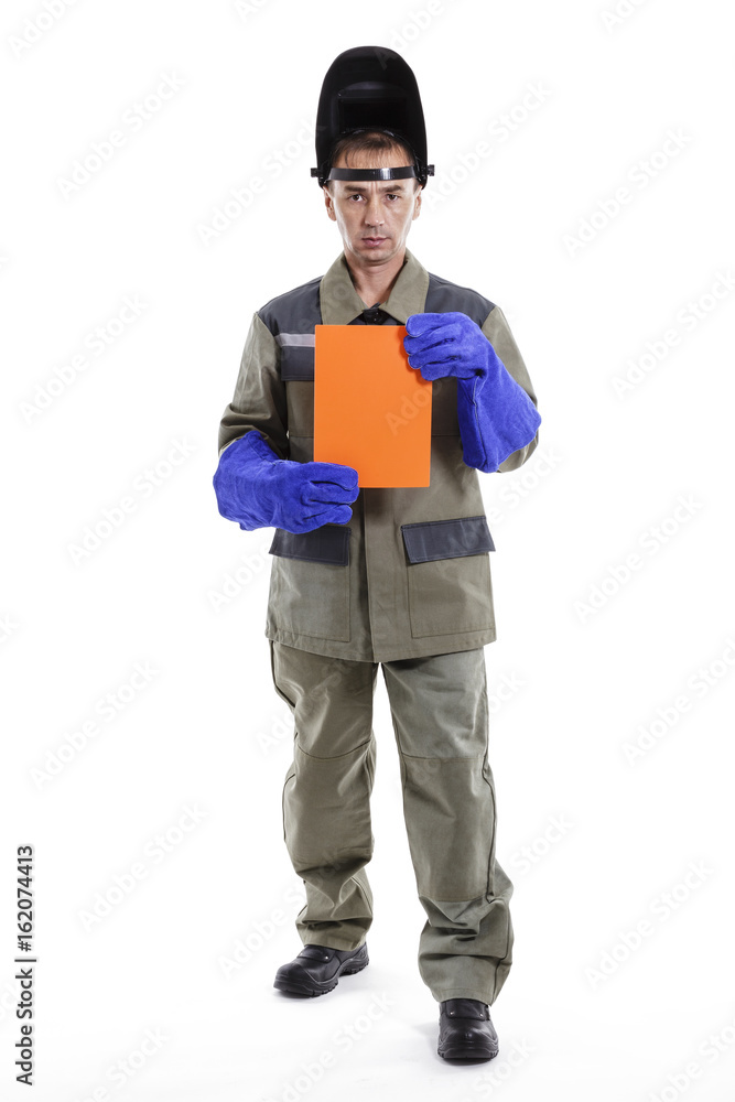 Welder with a welding mask and blue protective gloves holds an orange sheet Welder with a welding mask and blue protective gloves holds an orange sheet