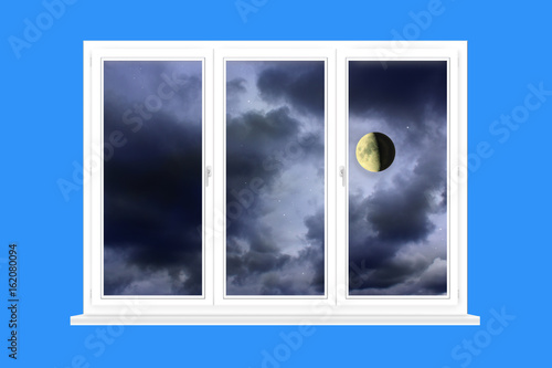window with view to Moon on the dark cloudy sky